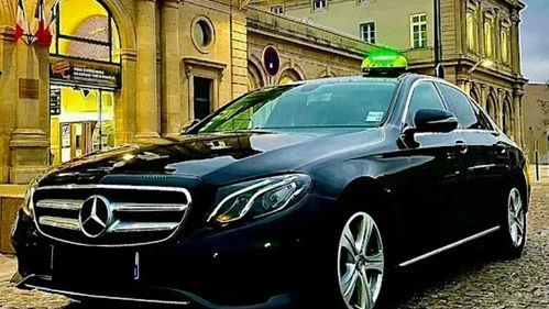 taxi Saint Marcellin Taxi noir Mercedes-Benz devant un bâtiment ancien avec un toit panoramique.