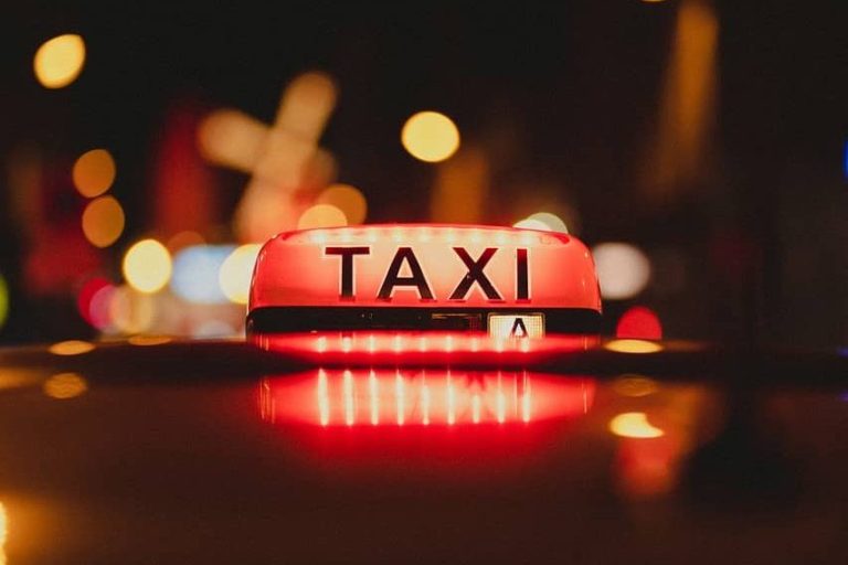 Signe lumineux "TAXI" avec fond flou de lumière urbaine.